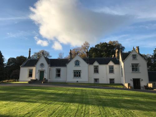 una gran casa blanca con un gran campo de césped en West Plean House en Stirling