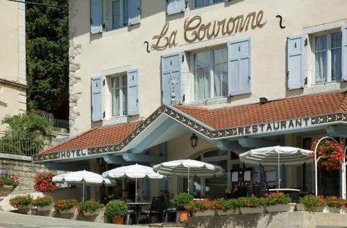 a building with tables and umbrellas in front of it at La Couronne in Jougne