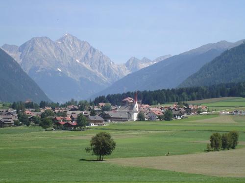 a village in a field with mountains in the background at Sporthotel Rasen in Rasùn di Sotto