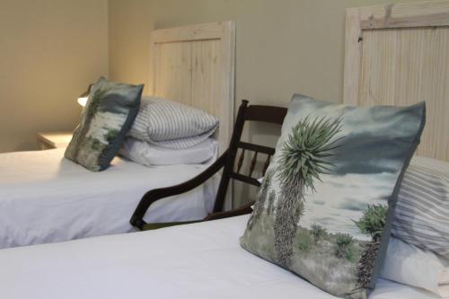 a bedroom with two beds and a pillow with a palm tree on it at Ripple Hill Hotel in Patensie