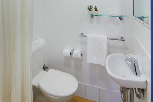 a white bathroom with a toilet and a sink at ibis Budget Perth Airport in Perth