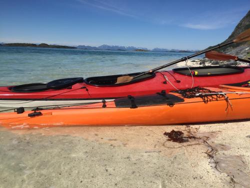 an orange kayak sitting on the beach next to the water at Steigen Lodge Sjøhytter in Engeløya