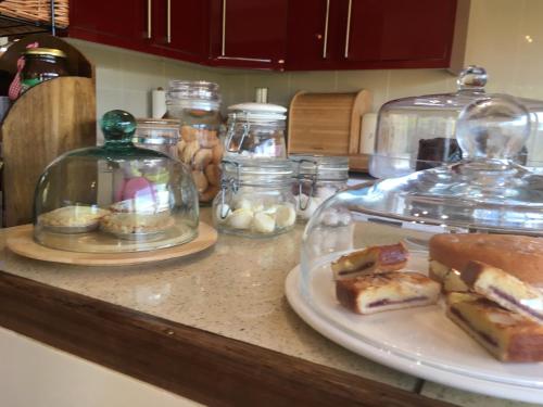 a counter with glass jars and a plate of food at Glan Llyn Farm House in Mold