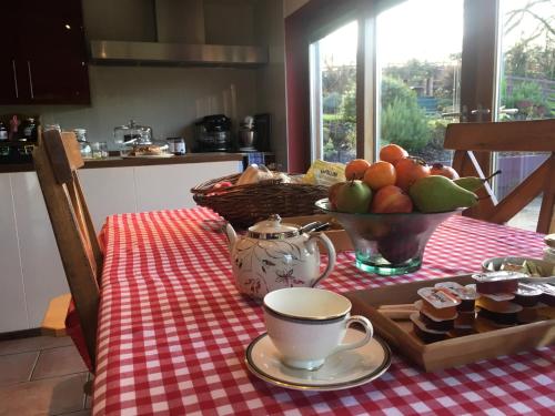a table with a bowl of fruit and a cup of coffee at Glan Llyn Farm House in Mold