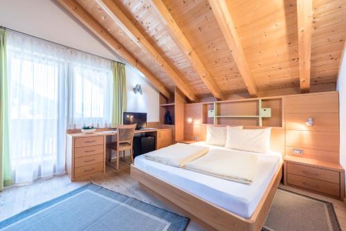 a bedroom with a bed and a desk with a computer at Ciasa Mascotte in San Vigilio Di Marebbe