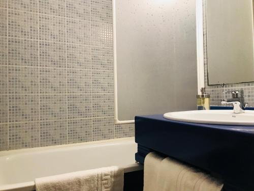 a bathroom with a sink and a tub and a mirror at Tourhôtel in Béthune