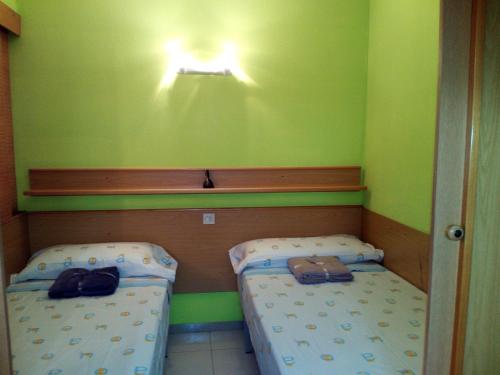 two beds in a small room with green walls at Apartamento Salou, playas, piscina in Salou