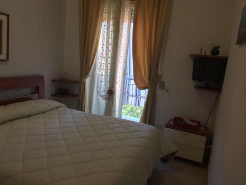 a bedroom with a white bed and a window at Cordovena in Capo dʼOrlando