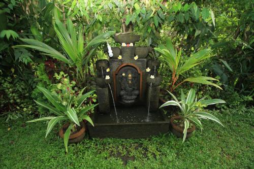 a fountain in a garden with two plants at Teba Jati Guest House in Ubud