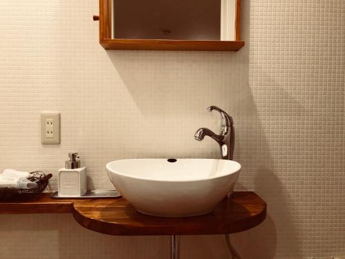 a bathroom with a white bowl sink on a wooden counter at Pension Razteca in Hakuba