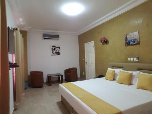 sypialnia z dużym białym łóżkiem z żółtymi poduszkami w obiekcie Hôtel YABISSO w mieście Lomé