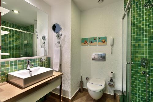 a green tiled bathroom with a sink and a toilet at Sunis Evren Beach Resort Hotel & Spa in Side