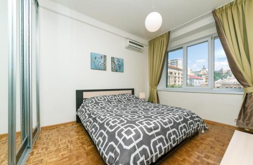 a bedroom with a bed and a large window at Alma Apartments in Kyiv