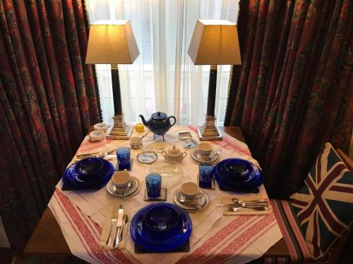 a table with two lamps and blue dishes on it at Wynberg House Bed & Breakfast Swansea in Swansea