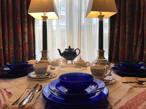 a table with blue dishes and lamps on a table at Wynberg House Bed & Breakfast Swansea in Swansea