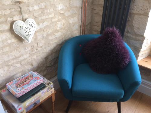 a blue chair with a purple pillow on a table at Upper Flat, The Manse, Painswick in Painswick