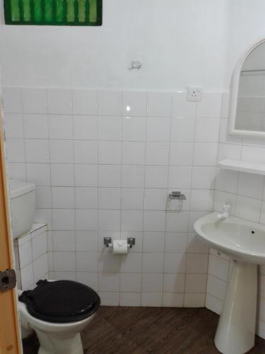 a bathroom with a black toilet and a sink at Calm Garden Cabanas in Tangalle