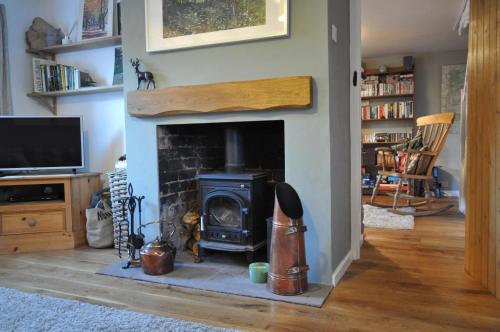 a fireplace in a living room with a stove at Foxglove Cottage in Clearwell