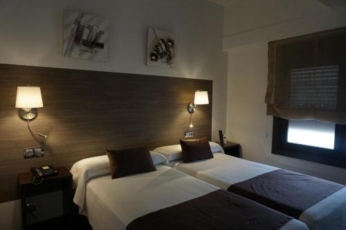 a hotel room with two beds and a window at Suites Coruña in A Coruña