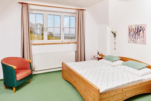a bedroom with a bed and a chair and a window at Hotel Garni Schöne Aussichten in Klöch