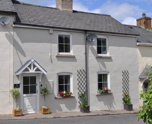 a white house with flowers in the windows at Foxglove Cottage in Clearwell