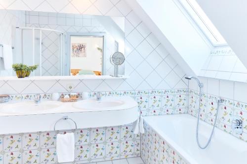 ein Badezimmer mit 2 Waschbecken und einer Badewanne in der Unterkunft Hotel Garni Schöne Aussichten in Klöch