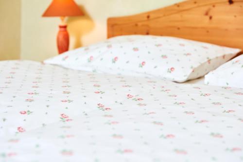 a bed with white sheets with pink flowers on it at Hotel Garni Schöne Aussichten in Klöch