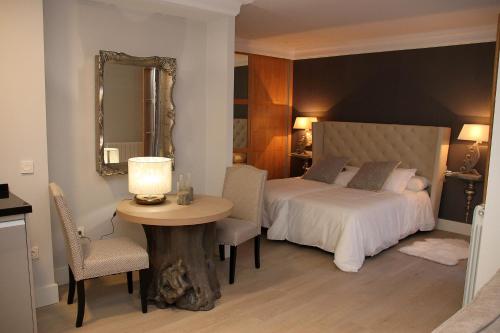 a bedroom with a bed and a table and a mirror at Principia Suites in León