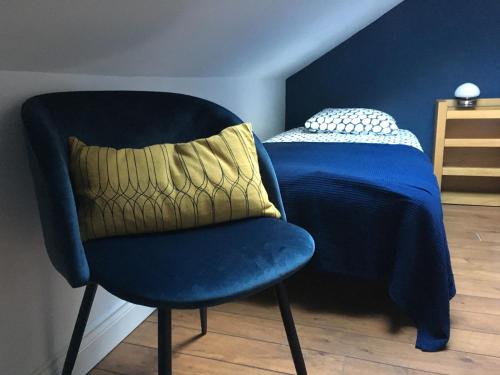 a blue chair with a pillow next to a bed at Les Jardins de l'Ile in Longeville-lès-Metz