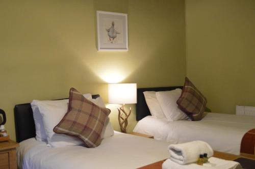 a hotel room with two beds and a lamp at The Buck Inn, Malham in Malham
