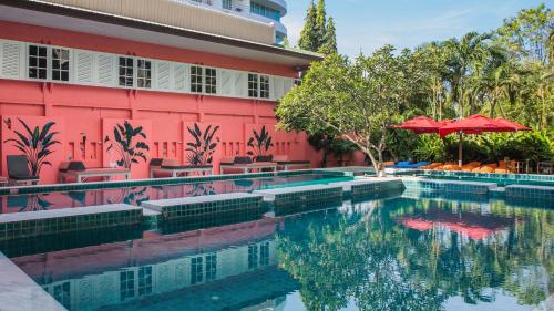 a swimming pool in front of a building with a red building at Sandalay Resort in Pattaya