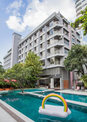 a hotel swimming pool with a rainbow in front of a building at Sandalay Resort in Pattaya