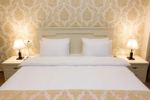 a bedroom with a large white bed with two lamps at Orchid Boutique Hotel in Tbilisi City