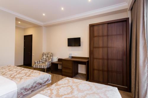 a bedroom with a bed and a desk and a television at Orchid Boutique Hotel in Tbilisi City