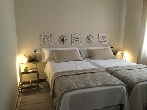コルドバにあるImágenes de Vianaのベッドルーム1室(ベッド2台付)、壁にランプ2つ