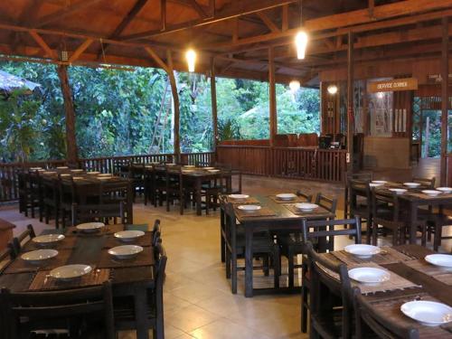 un restaurante con mesas de madera, sillas y árboles en Kadidiri Paradise, en Batudaka