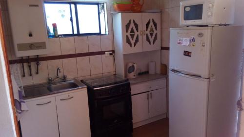 a small kitchen with a refrigerator and a sink at Cabaña 1 Neuling-Reñaca in Viña del Mar