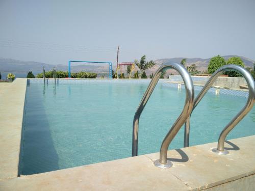 - une piscine avec deux mains courantes en métal à côté dans l'établissement Kunjwan Resort, à Bhor