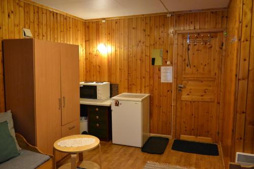 a kitchen with wooden walls and a refrigerator and a microwave at Alta River Camping in Alta