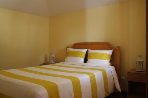 a bedroom with a large bed with yellow and white stripes at One Love Maktub in Paul do Mar
