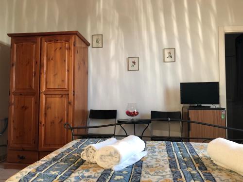 - une chambre avec un lit, une commode et une télévision dans l'établissement Agriturismo Azienda Agricola La Roccaia, à San Gimignano
