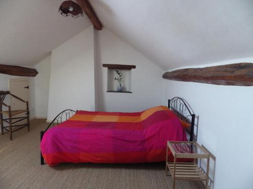 um quarto com uma cama com um cobertor colorido em Gite, Close To Hautecombe Abbey, Lac du Bourget em Grumeau