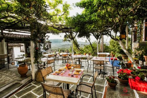 un restaurante al aire libre con mesas, sillas y árboles en Archontiko Soulioti, en Ayiá