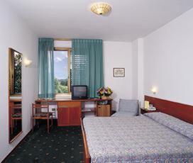 レッジェッロにあるPark Hotel Galileoのベッド2台、デスク、コンピュータが備わるホテルルームです。