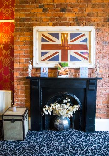 a black fireplace with a vase of flowers next to a brick wall at Hedley House Hotel & Apartments in York