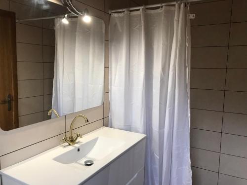 a bathroom with a sink and a white shower curtain at Can Berge in Figueres