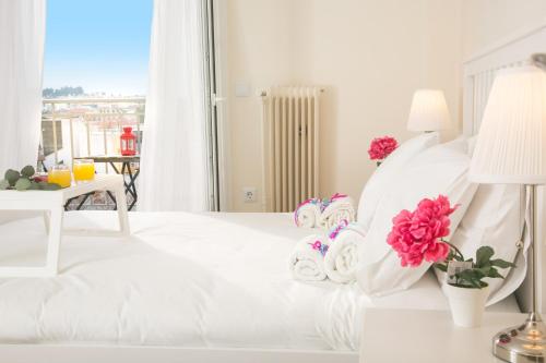 アテネにあるMagnificent luxury retrostyle flat Acropolis viewの白いベッドルーム(花の飾られた白いベッド付)