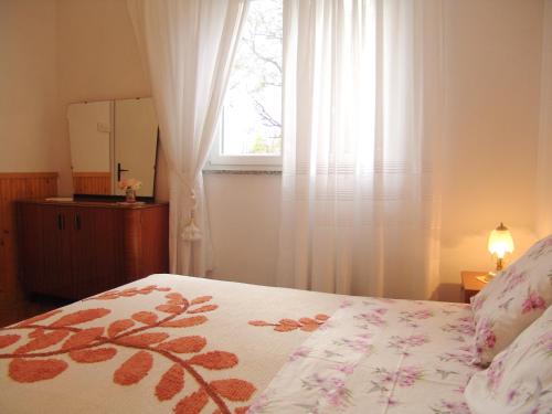 a bedroom with a bed with a window and a dresser at Sobe Bozica in Krk