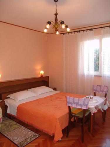 a bedroom with a bed and a table and a window at Sobe Bozica in Krk