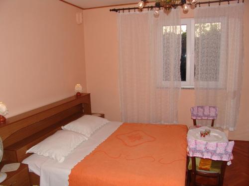 a bedroom with a bed and two chairs and a window at Sobe Bozica in Krk